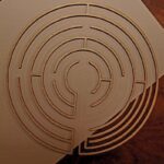 Voorbeeld van een half labyrint, met een vel papier er half doorheen gestoken, waardoor de baan deels is afgedekt.