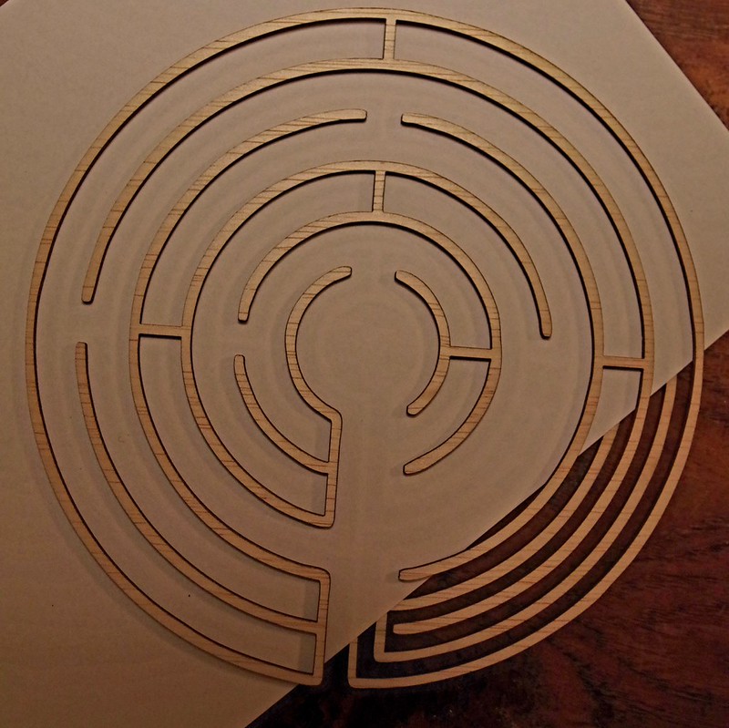 Voorbeeld van een half labyrint, met een vel papier er half doorheen gestoken, waardoor de baan deels is afgedekt.