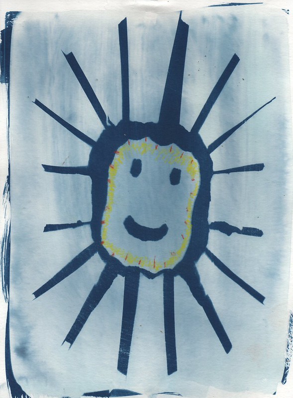 A4 met cyanotpe van een tekening van een lachende zon, met daarin kleuraccenten aangebracht met krijt.